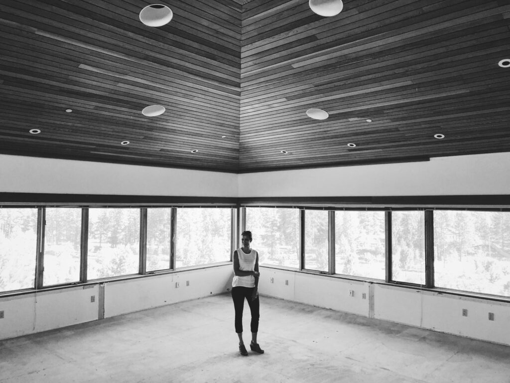 Black and white photo of a woman standing in an empty room during construction of The Haven.