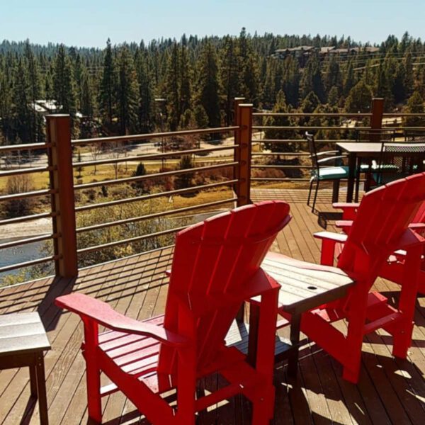 Two red lounge chairs on the deck outside at The Haven, overlooking the Deschutes River on a clear beautiful day.