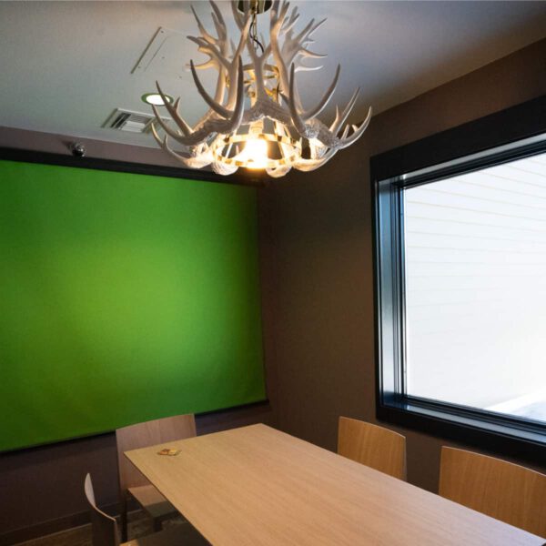 The podcast room at The Haven, showing a greenscreen, conference table, and antler overhead lighting.