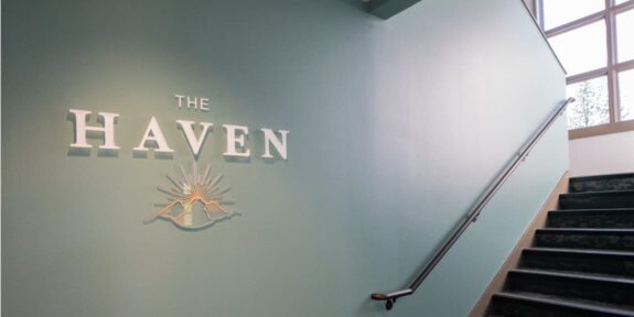The stairway leading up to The Haven, with the logo displayed on the wall.
