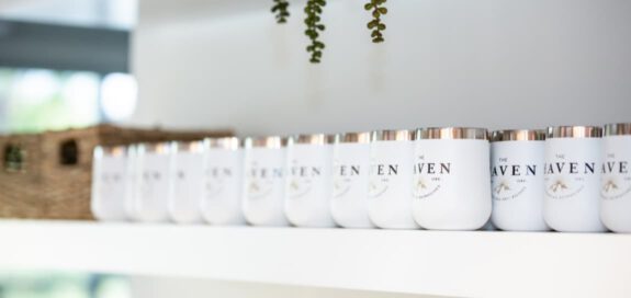 An arrangement of white Haven branded Hydroflask mugs on a shelf in the kitchen.