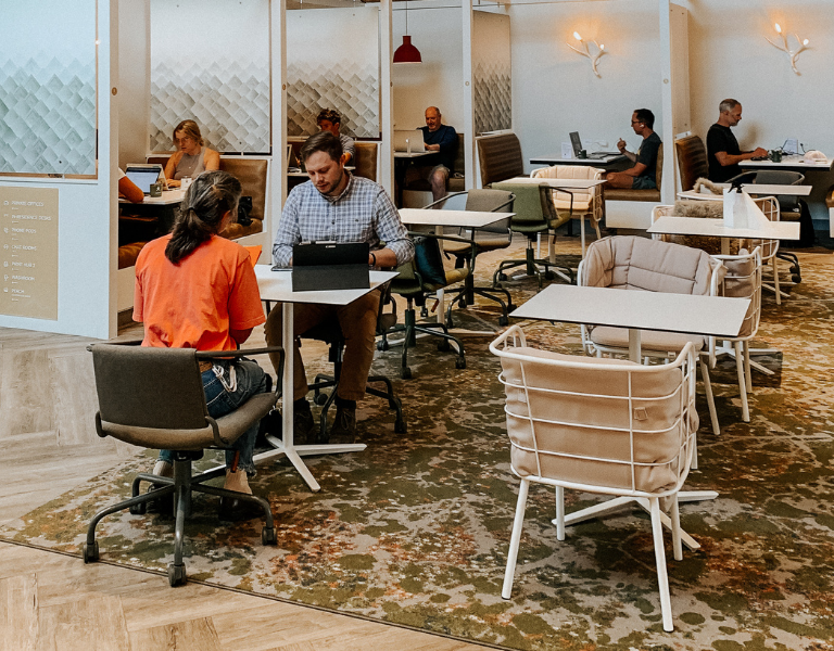 group of remote workers sit at small tables in the cafe of the haven coworking space