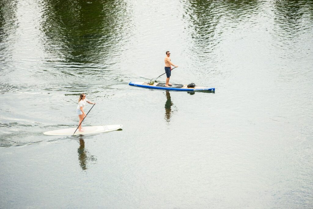 two people paddle board on the deschutes river in bend oregon from the view of the haven coworking space second story deck