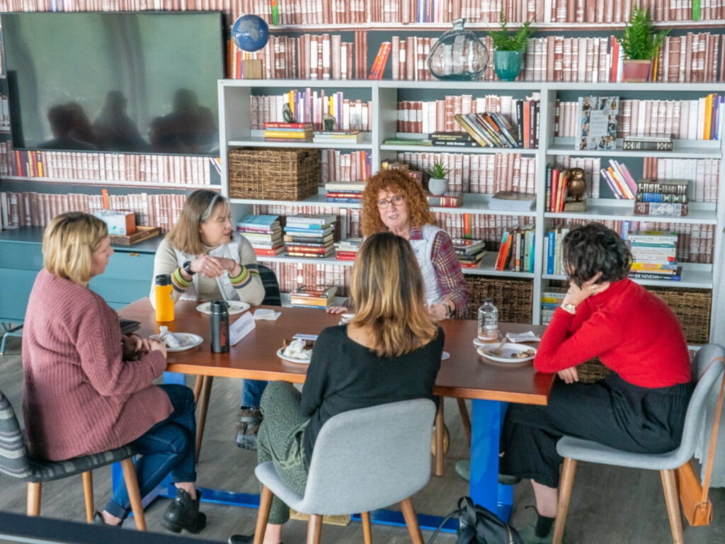 women gather around a table in a library discussing the benefits of flexible work spaces