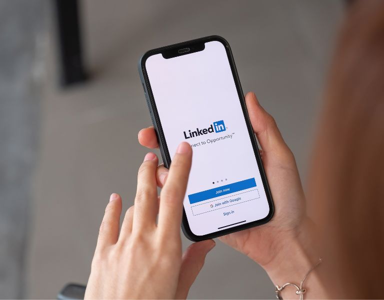 person holds a phone with the LinkedIn app open