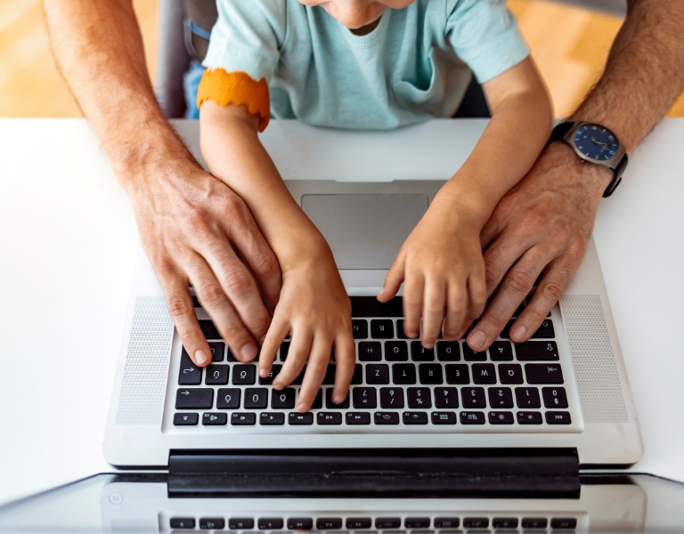 working parent shares the laptop keyboard with their child